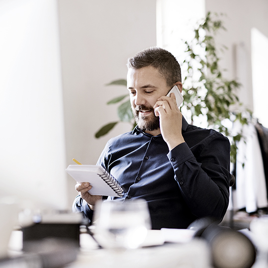 Mann am telefon mit Notizblock in der Hand